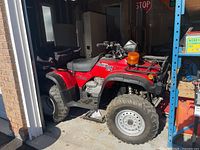 Side view of red Honda Foreman ES 4x4 ATV showing body panels and rack
