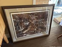 Frontal view of the framed print leaning against a wall, showing overall condition and mat details.