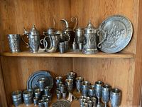 Full view of two shelves showing steins, pitchers, goblets, shot glasses and plates