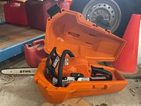 Open orange hard plastic case with Stihl MS 170 chainsaw resting inside
