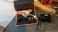 Overview of chainsaw kit in open soft case showing tool, battery, charger and case