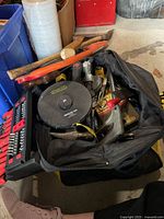 Black DeWalt tool bag filled with various hand tools including hammer, screwdrivers, and a Stanley fiberglass tape measure labeled '100'.