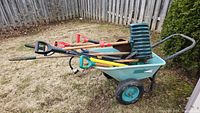 Wheelbarrow loaded with assorted wooden-handled tools under natural light