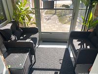 Two resin wicker-look chairs flanking a matching square glass-top table on a porch.