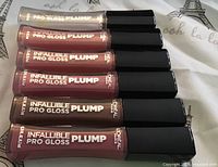 Top view showing all six sealed lip gloss tubes aligned horizontally with black caps and color visible in tubes.