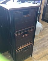 Front view of the wood organizing cabinet showing three drawers with integrated handles, dark brown finish, and visible wear.
