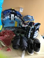 Overview of lot showing folded baby clothes, shoes, boots, and hat arranged on a flat surface