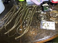 Multiple gold-tone costume jewelry necklaces displayed on table
