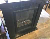 Wooden fireplace mantle with built-in electric fireplace insert and visible wear.