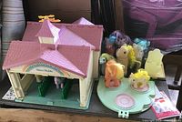My Little Pony plastic house/stable playset with a group of pony figures placed inside and around it on a black table