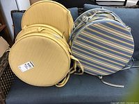 Four yellow striped round cushions and four blue and yellow striped round cushions stacked on a couch