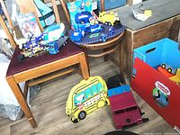 Two photos showing the vintage wooden Thomas the Train toy box and the assorted toys, including Paw Patrol and truck-themed toys.