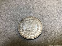 Top view of the reverse side of the coin showing eagle, text 'UNITED STATES OF AMERICA', 'ONE DOLLAR' and 'IN GOD WE TRUST'.