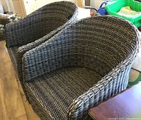 Two grey wicker outdoor patio chairs shown side by side, viewed from angle showing seat and backrest