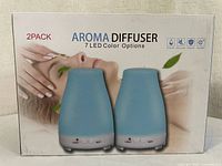 Photo showing packaging front with image of two blue aroma diffusers and LED light features.