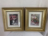 Photo showing both gold leaf framed floral prints side by side on a wall, highlighting the frames and floral motifs.