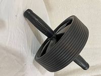 Black dual wheel ab roller on white background, showing angled view of wheels and textured handles.