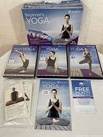 Full contents of the Gaiam Beginner's Yoga Kit arranged for display including 3 DVDs, printed pose guide, pose cards, and trial card.