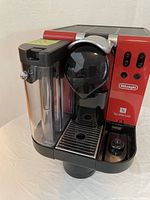 Front angled view showing water reservoir, drip tray, buttons and red-black casing.