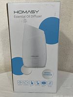 Front view of the Homasy Essential Oil Diffuser box showing product image, brand name, model number, and basic features icons.