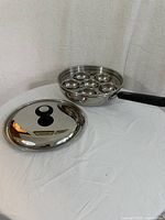 Full view of egg poacher pan with lid removed showing 6 individual egg poaching cups.