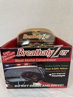 Front view of BreathalyZer packaged in box with branding and BAC color indicators, includes mention of super bright LED flashlight and one-touch operation