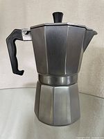Side view of the small stovetop espresso maker showing the aluminum octagonal body and black plastic handle.