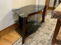 Side angle view of Bell'O television console showing curved wooden frame and three tempered smoked glass shelves with smooth finish.