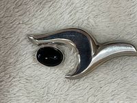 Silver abstract wave or seagull shaped pin with polished black oval cabochon stone mounted.