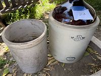 Jug and crock shown outdoors on the ground. Jug wide with brown glazed top and crock plain.