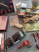 Overview of assorted collectibles including giant lighter, vintage clock with dice, miniature fire truck toy, pipe, matches, and Band-Aids