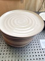 Stack of Crate & Barrel 18th Street dinner plates showing the off-white glazed ceramic with concentric ring texture and some imperfections