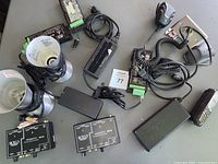 Overview of the lot showing various electronic items including two lava lamp bases, stereo converters, power supply, coiled handset, and cables.