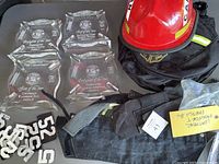Firefighter awards, leather badge numbers, black protective gear, and red firefighter captain helmet shown together.
