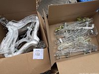 Box containing stack of clear plastic molded hangers for tops, showing shape and size