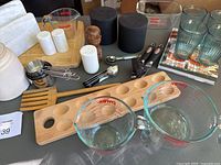 Overview photo of the collection including CB2 canisters, wooden egg holder, measuring cups, glassware, and utensils.