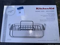 Box of KitchenAid Gourmet Series stainless steel roaster pan with nonstick U-shaped rack, showing front branding and product details.