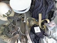 Photo showing two white helmets, gray harness, camo shirt, white belt, black gloves, and military pins.