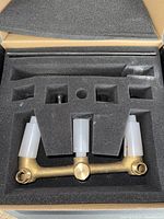 Overhead view of the brass valve body component of the wall mount faucet inside foam packaging.