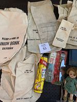 Off-white cotton vintage bank coin bags with printed text for Bank of America and Union Bank along with some vintage items including Pixie Pick Up Stix game and pencils.