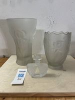The three frosted glass pieces: two larger vases and one smaller perfume bottle, all displayed upright to show size and form.