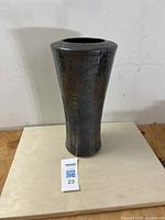 Full front view of the flared stoneware vase on a wooden surface against a plain background