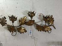Front view of the gilt metal wall sconce showing three floral candle cups and surrounding sculptural leaves.