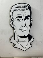 Front view of the "Jocko H" pop art piece mounted on a white wall, showing the graphic black and white stylized male head with slicked-back hair.