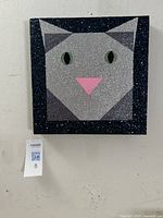 Front view of square mixed-media glitter portrait of gray cat with green eyes, pink nose, on canvas with black glitter frame.