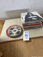 Stack of loose 45 RPM records and sleeved singles on wooden surface