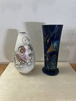 Photo of both mid-century Sacha Brastoff vases side by side on a flat surface, showing front designs.