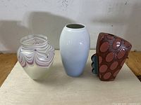 Full view of three collectible vases showing different styles: iridescent glass, porcelain floral, and hand-painted ceramic