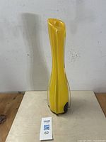 Front view of tall yellow art glass vase with aubergine base accents and clear outer layer, placed on wooden surface.