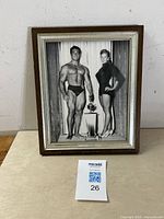 Framed black-and-white photograph of Tom Sansone and a woman with a trophy, showing front view of frame and photograph content.